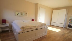 A bedroom with a bed, a nightstand, a wardrobe, and a bookshelf.