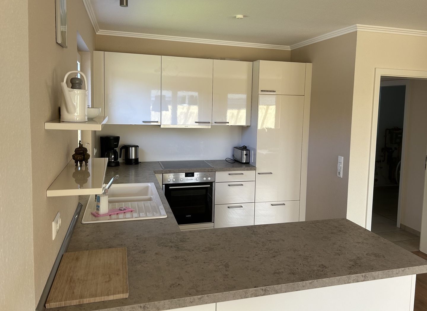 A modern kitchen with white cabinets, a stainless steel oven, and a coffee maker.