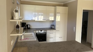 A modern kitchen with white cabinets, a stainless steel oven, and a coffee maker.