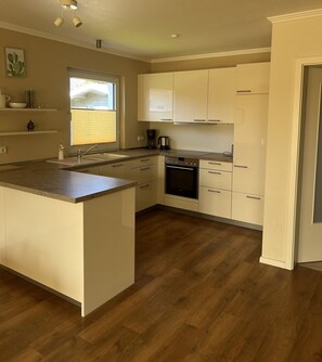 A kitchen with a central island, a built-in oven, and a window with blinds.
