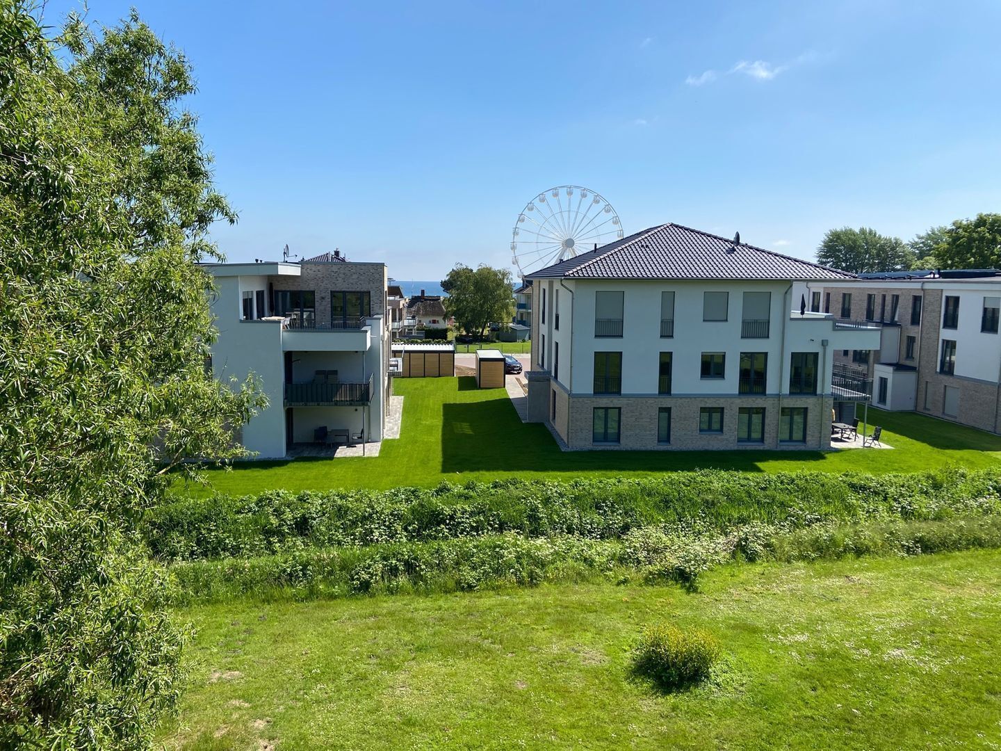 Un quartier résidentiel avec des maisons modernes, une pelouse bien entretenue et une grande grande roue en arrière-plan.