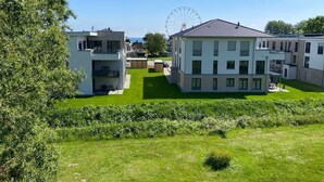A residential area with modern houses, a well-maintained lawn, and a large Ferris wheel in the background. - 7016 "incl. beach chair" - 7016 "incl. beach chair" - An der Aue 9c - Apartment 25 (Dahme)