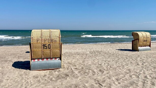Two wicker beach chairs with metal bases on a sandy beach with the ocean in the background. - 7016 "incl. beach chair" - 7016 "incl. beach chair" - An der Aue 9c - Apartment 25 (Dahme)