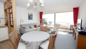 Ein modernes Wohnzimmer mit einem runden Tisch, Sofas und einem Balkon mit Sitzgelegenheit.