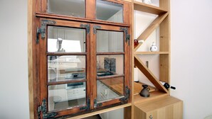 Ein Holzkabinet mit Glastüren, eine Weinflasche und eine Vase auf einem Regal.