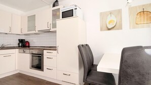 Une cuisine moderne avec des meubles blancs, un four à micro-ondes, une machine à café et un coin repas comprenant une table et des chaises.