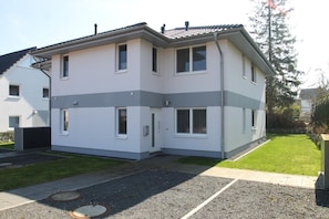 Ein zweistöckiges Gebäude mit flachem Dach, zahlreichen Fenstern und einem kleinen Vorgarten mit befestigter Auffahrt.