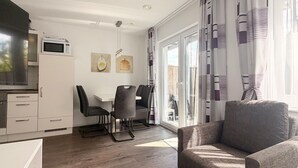 Une cuisine moderne équipée d’un four à micro-ondes, d’une table à manger avec des chaises et d’un canapé, le tout dans une pièce lumineuse dotée de grandes fenêtres.