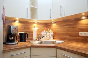 Eine moderne Küche mit Holzarbeitsplatten, einer Kaffeemaschine, einem Spülbecken und Schränken.