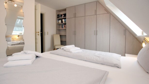 Ein modernes Schlafzimmer mit zwei Betten, einem Einbauschrank und einem Oberlicht.