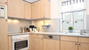 Eine Küche mit Holzausstattung, einem eingebauten Backofen, einer Kaffeemaschine und einem Fenster mit herzförmigen Verzierungen.