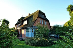 Een traditioneel bakstenen huis met een steile dakschild, een klein portaaltje en een tuinkamer.