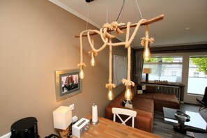 Un salon chaleureux avec une table basse en bois, un canapé marron et un luminaire suspendu dont les ampoules sont apparentes.