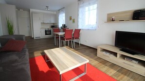 Een modern appartement met een woonkamer, eetgedeelte, keuken en een televisie.