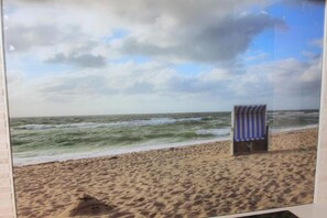 A beach scene with a striped beach chair and a sandy beach.