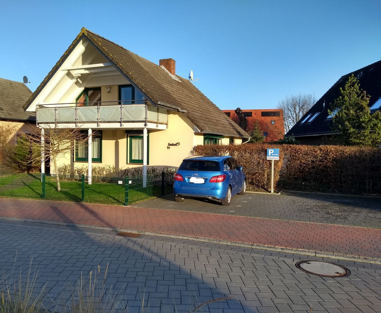 Ein zweistöckiges Haus mit einem blauen Auto auf der Auffahrt.