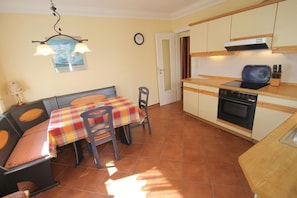 Cocina compacta con comedor, suelo de baldosas, estufa y mesa con sillas.