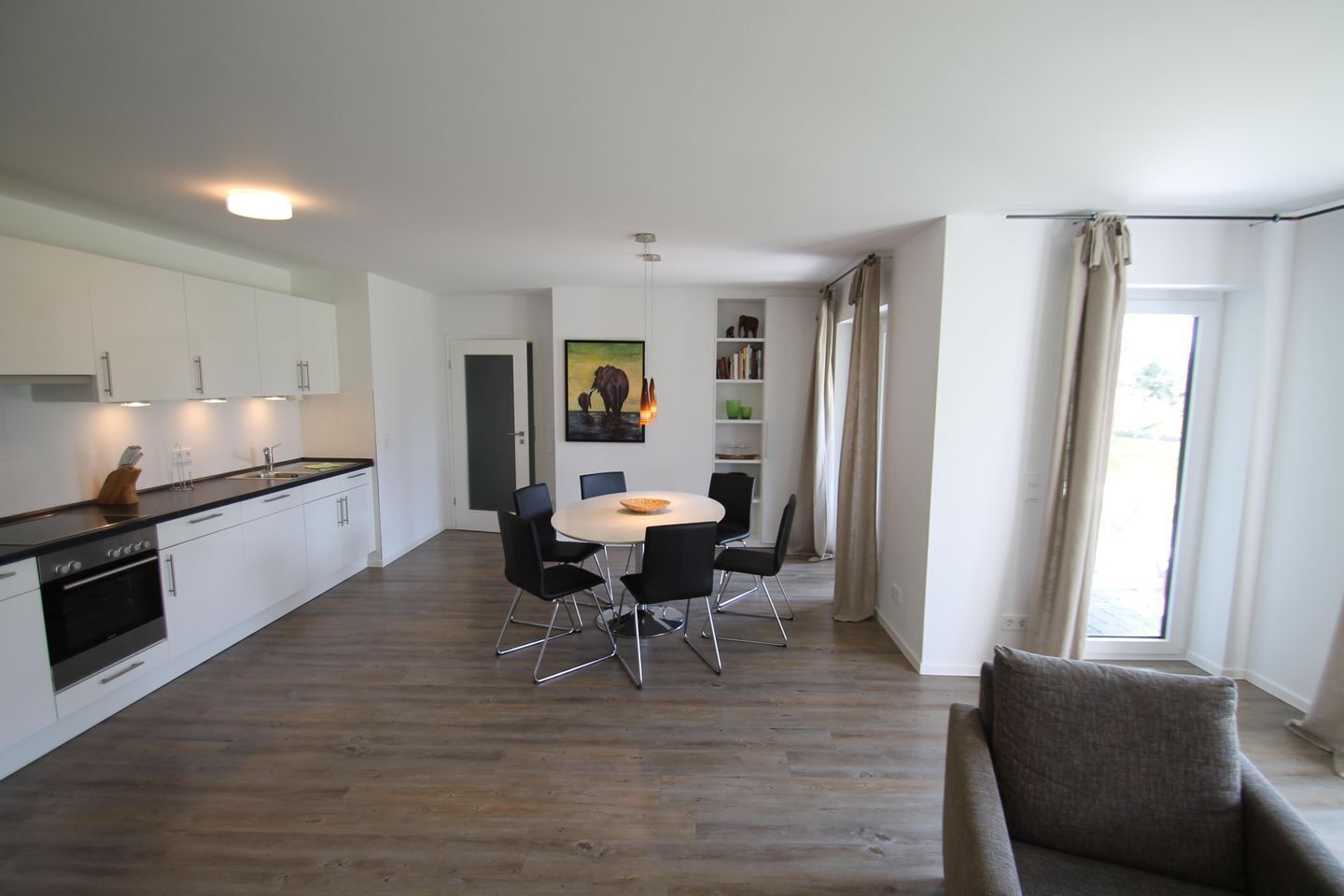 A modern kitchen with white cabinets and a dining area with a round table and black chairs.