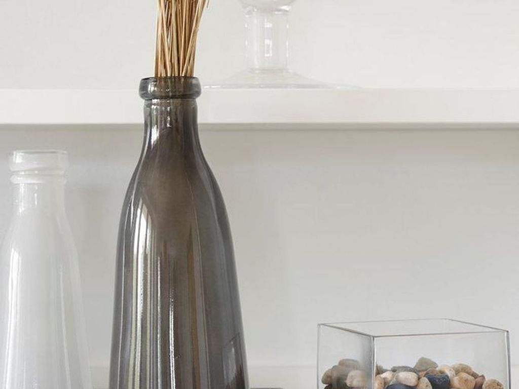 A dark glass bottle with a narrow neck and a clear stopper, placed on a white surface.