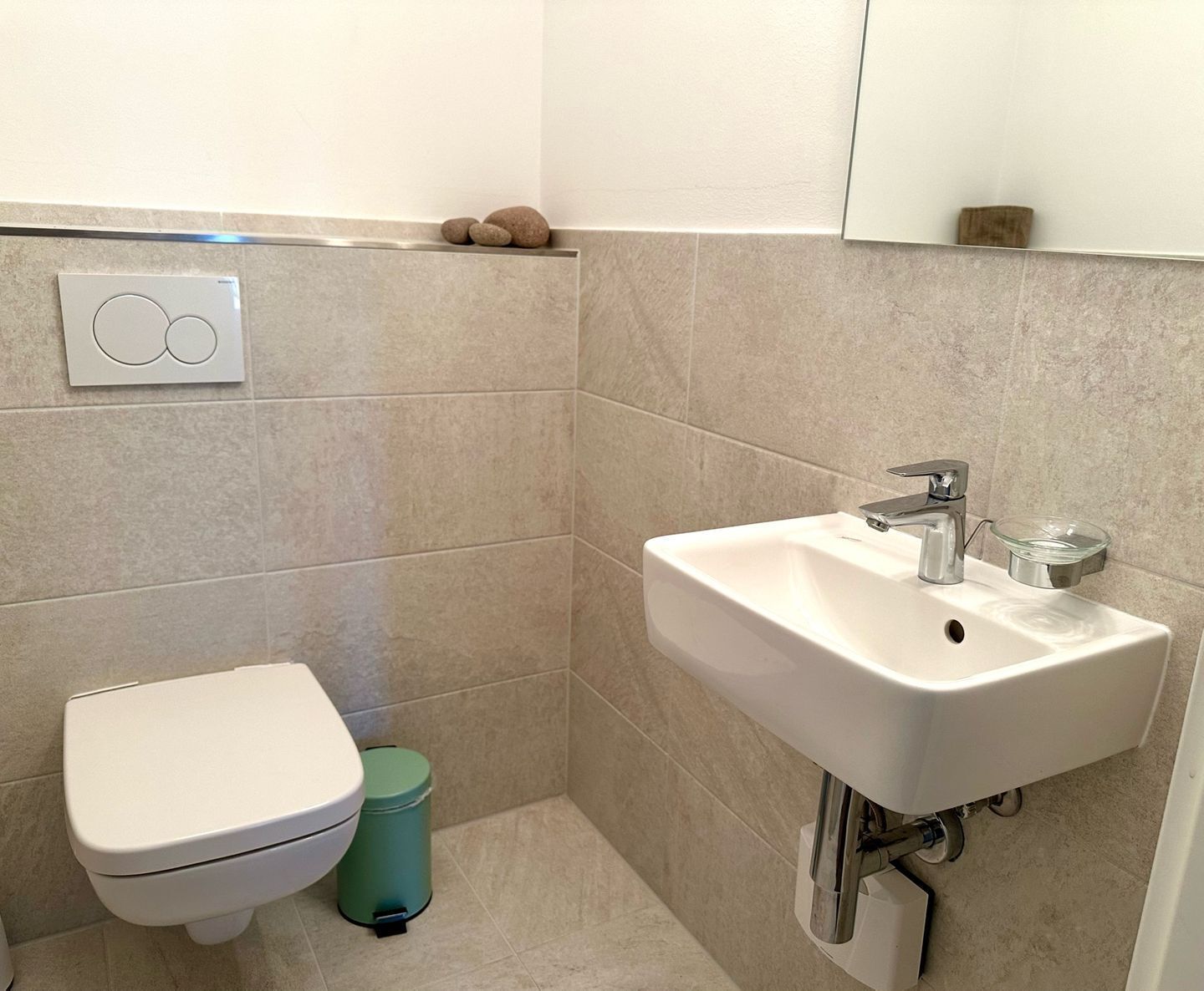A bathroom with a toilet, sink, and trash bin.