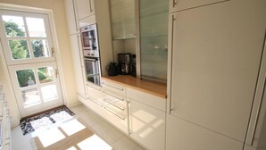 A modern kitchen with white cabinets, a wooden countertop, and a built-in oven.