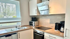 A compact kitchen with a dishwasher, microwave, stove, oven, and a coffee maker. - 1310 - House Greta - House Greta in Dahme 1310 (Dahme)