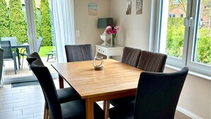 A dining area with a wooden table and black chairs, a hanging lamp, and a view of greenery outside. - 1310 - House Greta - House Greta in Dahme 1310 (Dahme)