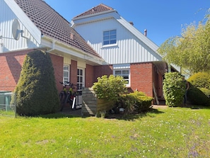A two-story house with a red brick facade, a white exterior, and a brown tiled roof.