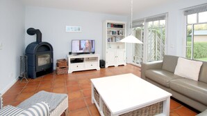 A living room with a fireplace, a television, a sofa, and a coffee table. - Wiesenweg 4a, Whg. 2 - Ferienwohnung mit 3- Zimmern auf ca. 120m² (Wyk auf Föhr)