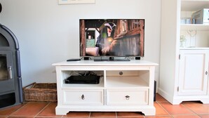 A white entertainment unit with a flat-screen TV, a remote control, and a cable box. - Wiesenweg 4a, Whg. 2 - Ferienwohnung mit 3- Zimmern auf ca. 120m² (Wyk auf Föhr)