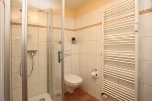 Ein Badezimmer mit Duschkabine, Toilette und Handtuchhalter.