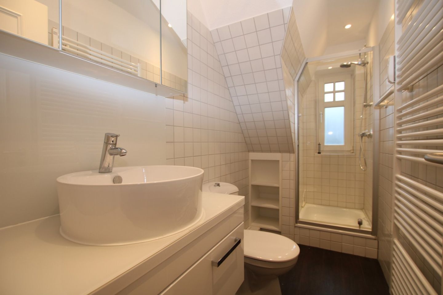 Ein modernes Badezimmer mit einem großen Waschbecken, Toilette und barrierefreier Dusche.