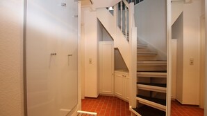 A hallway with a staircase, a door, and a radiator. - Am Grünstreifen 31, Whg. 6 "Strandgut" - Apartment for 2 persons on approx. (Wyk auf Föhr)