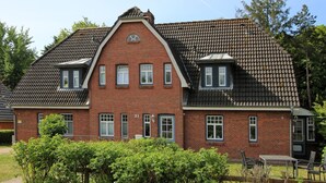 A two-story brick building with a gabled roof, multiple windows, and a visible number '31' on the facade. - Am Grünstreifen 31, Whg. 6 "Strandgut" - Apartment for 2 persons on approx. (Wyk auf Föhr)