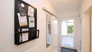 A hallway with a bulletin board displaying various notices and a door leading to a bright room. - Fasanenweg 2 b, Whg. 2 - vacation apartment in Wyk with 3 rooms, approx. 58 m² on the ground floor with (Wyk auf Föhr)