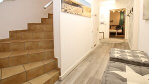 Un escalier menant à une chambre à coucher équipée d’un lit et d’une table de chevet.