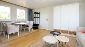 Een kamer met een eettafel, stoelen, een bank, een bijzettafeltje en een kledingkast.