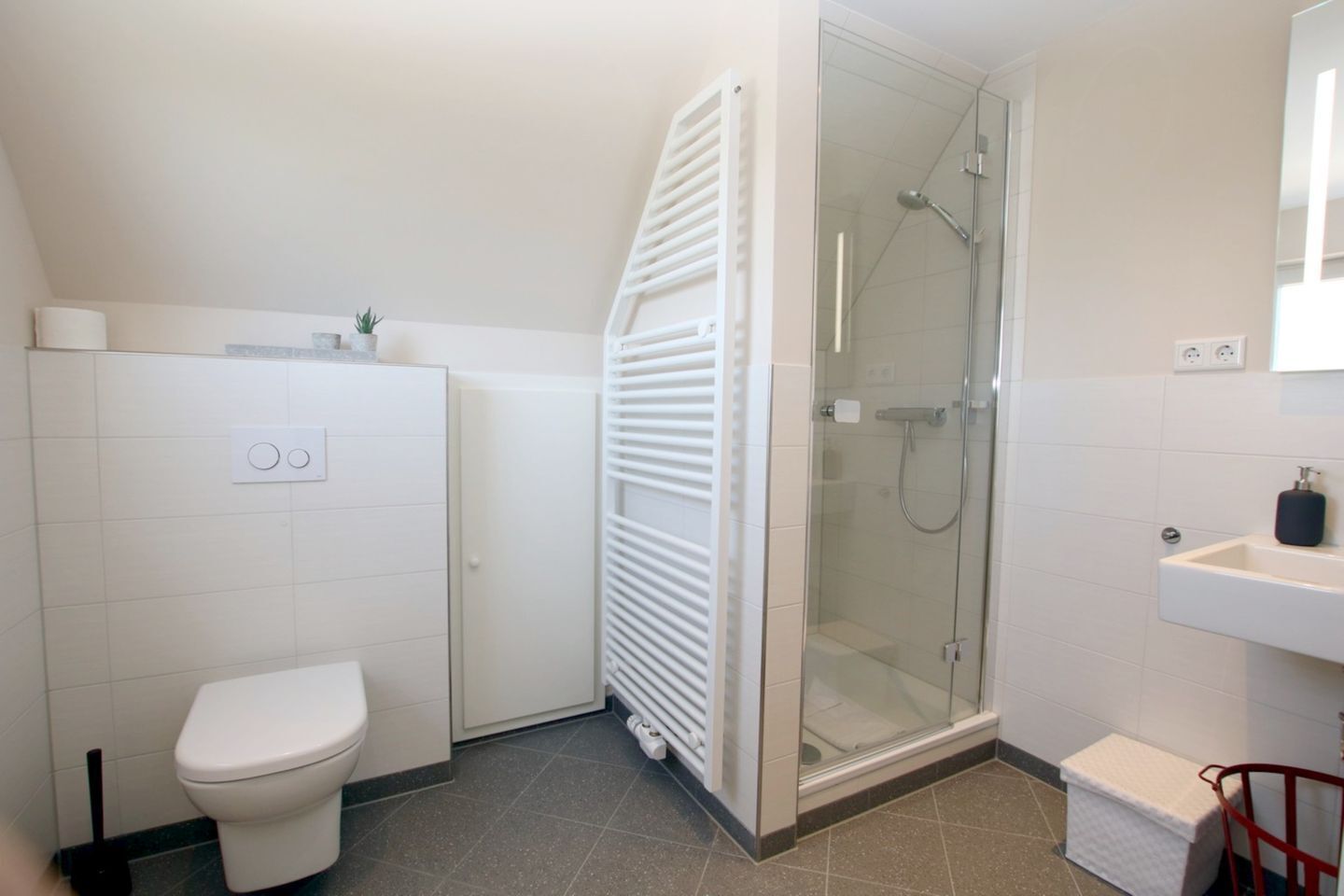 Un baño con inodoro, ducha, lavabo y radiador.