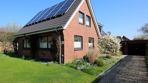 Een huis met zonnepanelen, een bakstenen gevel en een tuin.