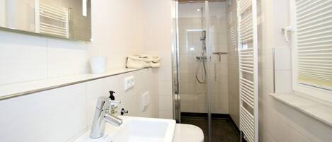 A modern bathroom with a white sink, toilet, and glass-enclosed shower.