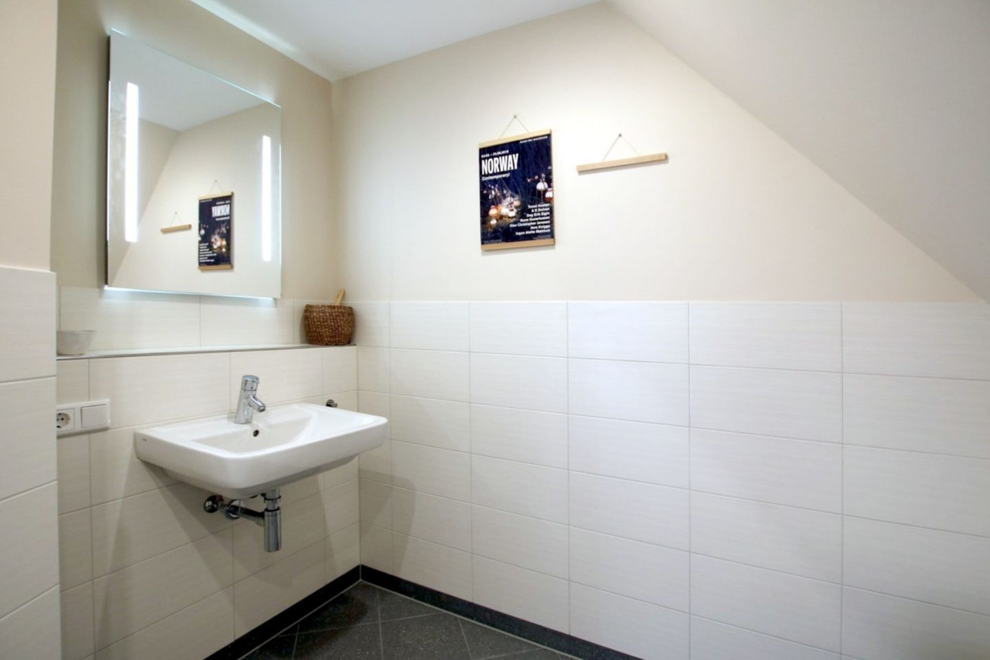A bathroom with a white sink, a mirror, and a poster on the wall.