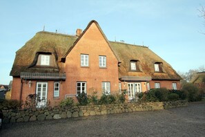 A two-story house with a steeply pitched roof, multiple windows, and a stone wall in front. - Dörpstraat 9, Whg. 3 - Holiday apartment with 3 rooms on approx. 49m² (Wyk auf Föhr)