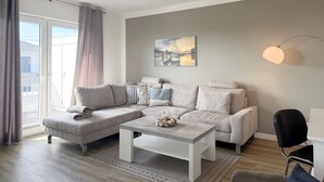 A modern living room with a grey sofa, a coffee table, and a painting on the wall. - 2107 - with sea view Strandwiese - 2107 - Penthouse Strandwiese 9 - Apartment 7 (Dahme)