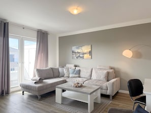 Un salon moderne avec un canapé gris, une table basse et un tableau accroché au mur.