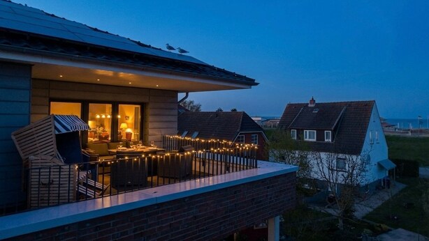 A residential building with a balcony, outdoor seating, and string lights. - 2107 - with sea view Strandwiese - 2107 - Penthouse Strandwiese 9 - Apartment 7 (Dahme)