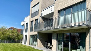 A modern multi-story residential building with balconies, large sliding glass doors, and a well-maintained lawn. - 2605 - Strandwiese 18 - Apartment 2605 in the Strandwiese (Dahme)