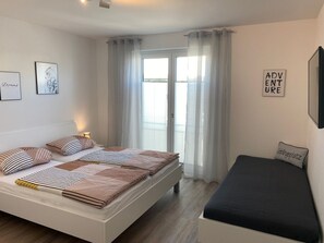 Une chambre à coucher moderne avec un lit, des tables de chevet et un petit canapé.
