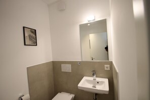 A bathroom with a white sink, a mirror, and a toilet. - 2606 - Strandwiese 18 - Apartment 2606 in the Strandwiese Dahme (Dahme)