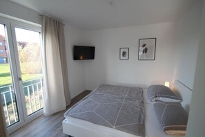 Un dormitorio con una cama, un televisor y dos cuadros colgados en la pared.