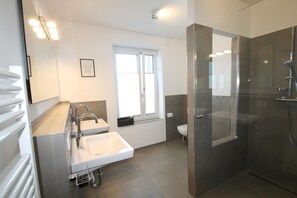 Une salle de bain moderne avec une douche à parois de verre, un double lavabo et des toilettes.